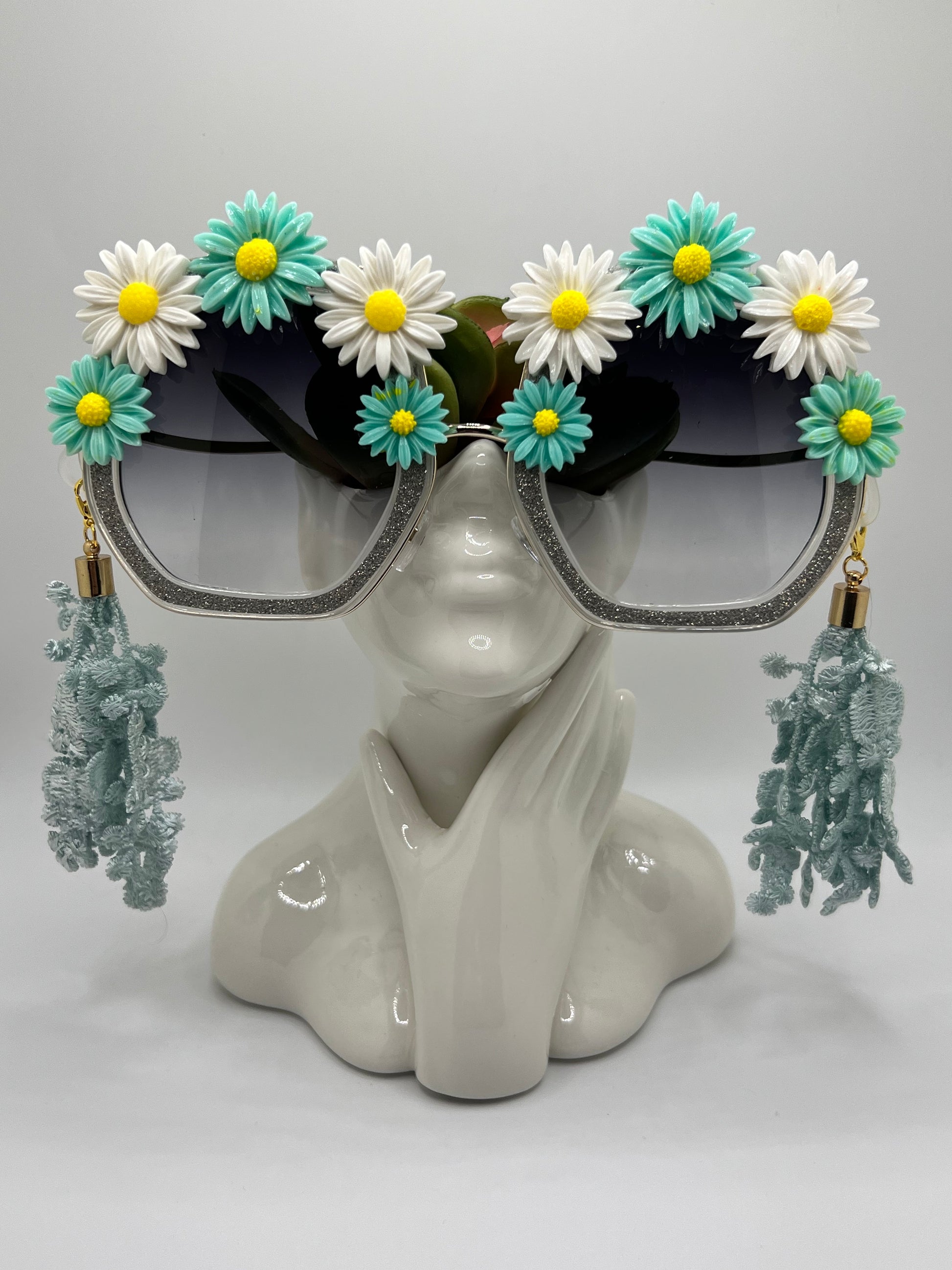 These shimmering silver frames are topped with icey, teal, and white daisies and come with removable lace tassels and a gold eyewear chain.