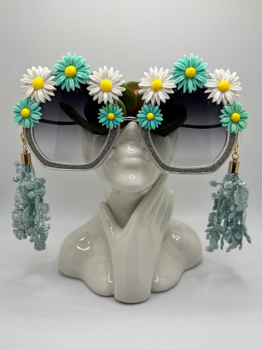 These shimmering silver frames are topped with icey, teal, and white daisies and come with removable lace tassels and a gold eyewear chain.