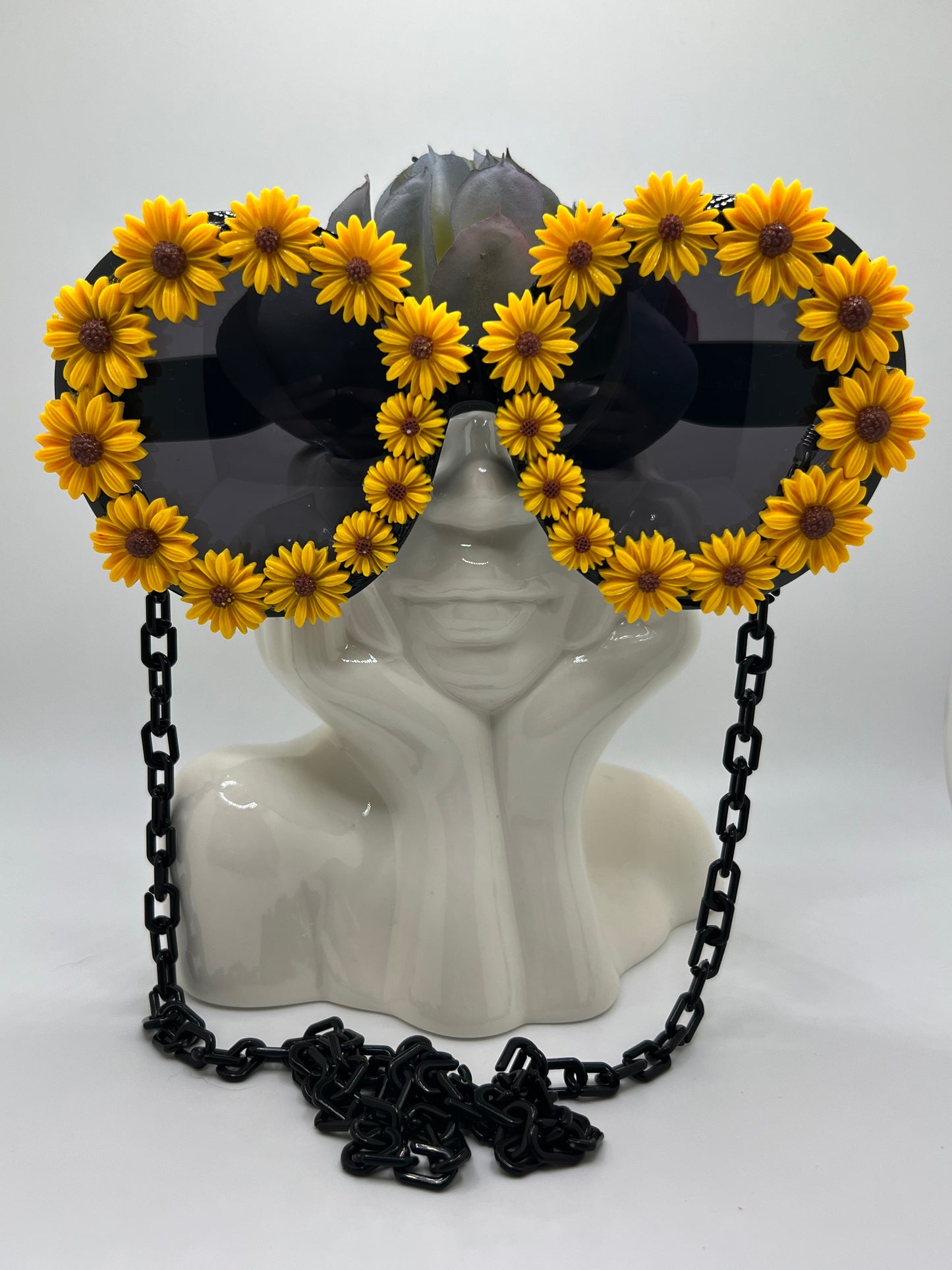 Bright sunflowers surround these oversized lenses and are accompanied by an adjustable and removable eyewear chain. 