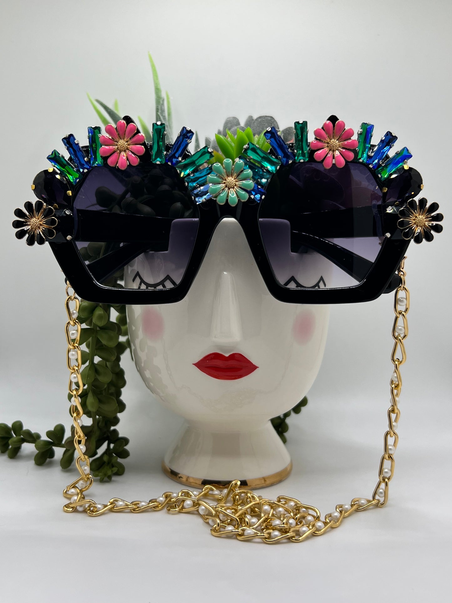 Sparkling rhinestones and bright flowers surround these polygon square sunglasses and are accompanied by an adjustable and removable eyewear chain.