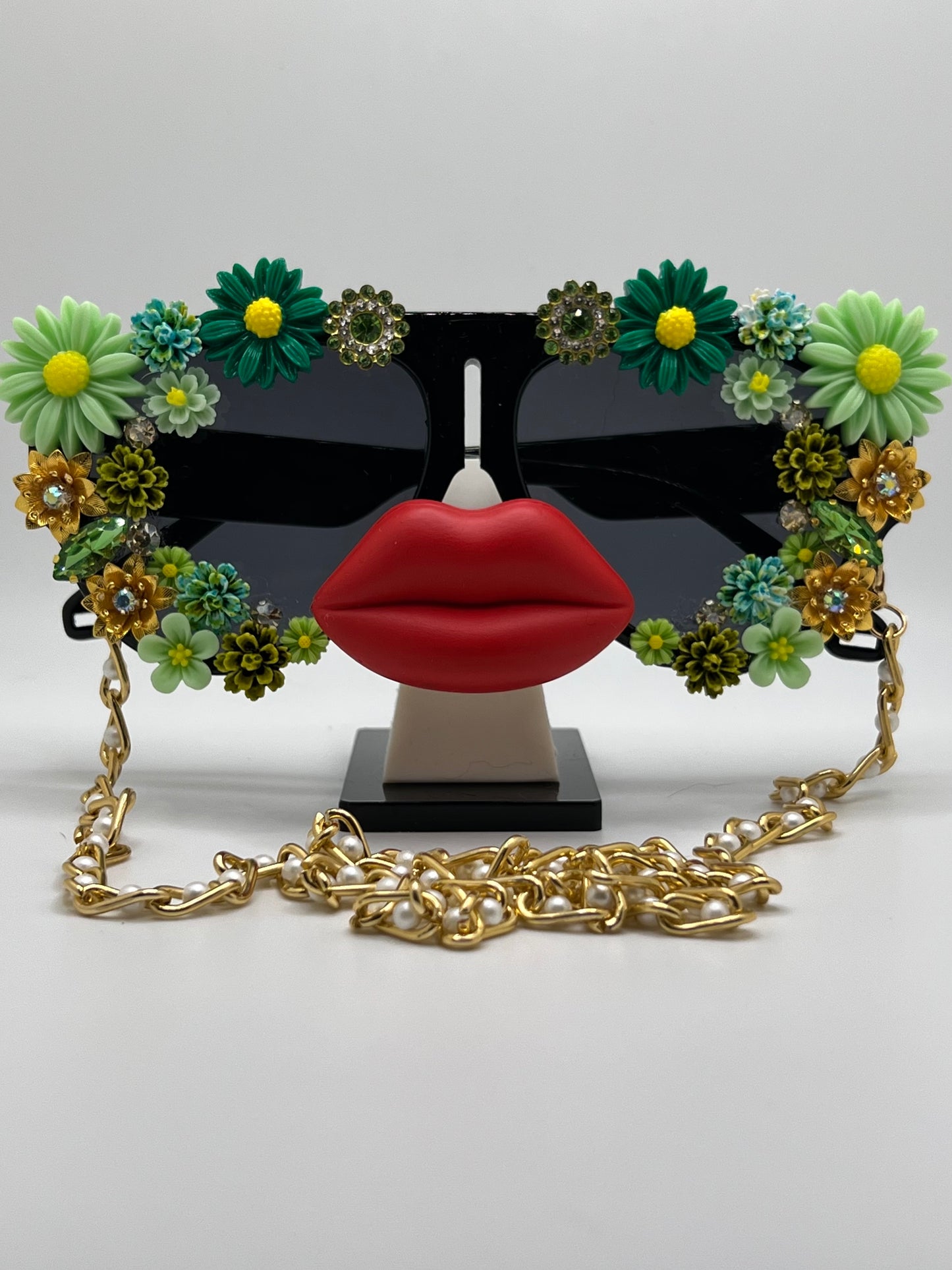 These oversized aviators are surrounded by hues of green and gold flowers and come with a removable gold chain.