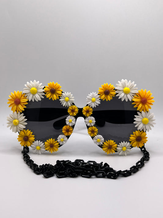 Bright daisies in yellow and white surround these oversized lenses and are accompanied by an adjustable and removable eyewear chain in black.