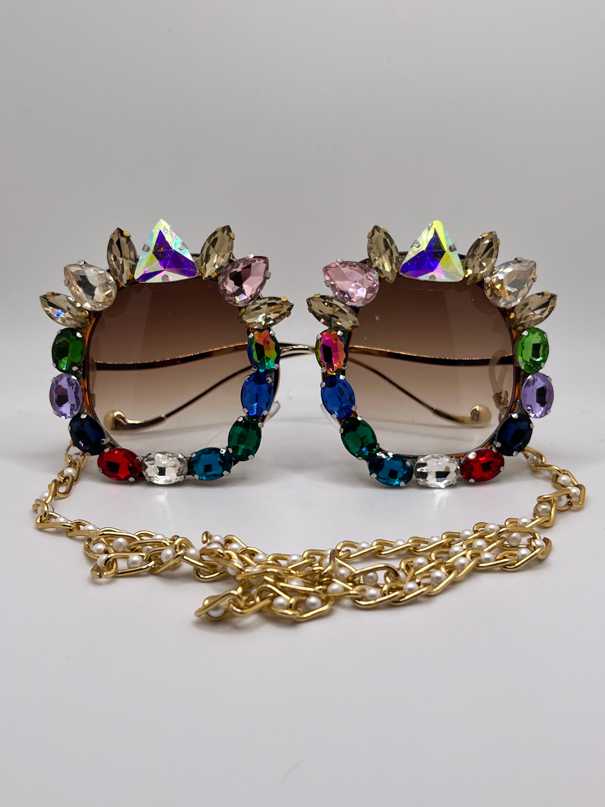 Sparkling rhinestones surround these oversized sunglasses and are accompanied by an adjustable and removable eyewear chain.