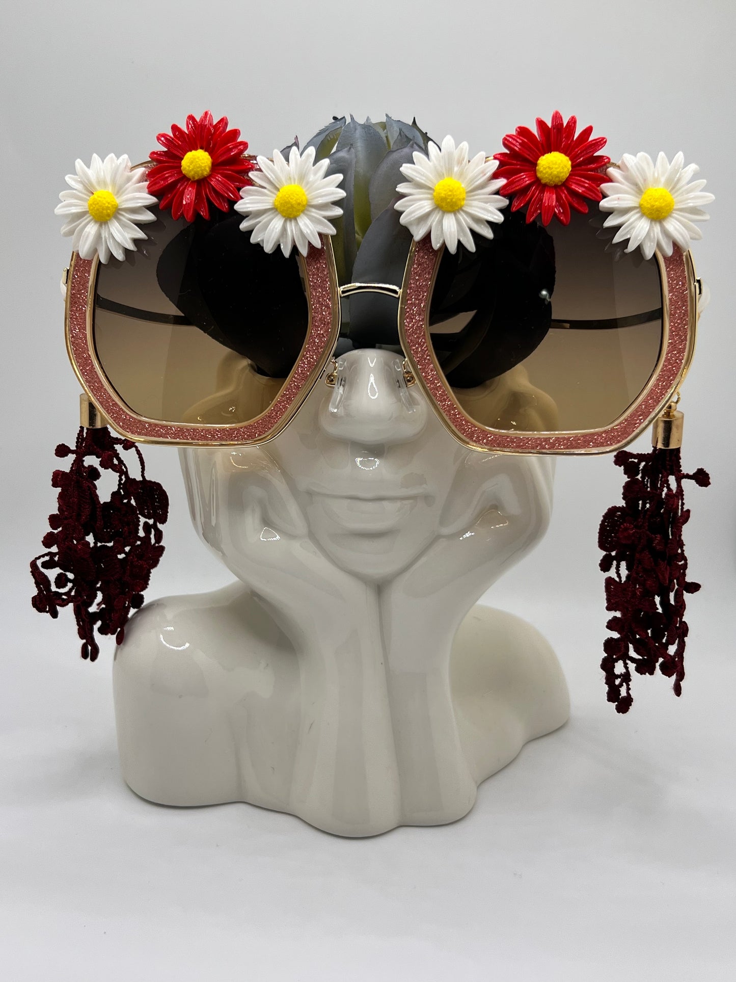 These glimmering red frames are embellished with giant white and red daisies and lace tassels in deep red. They also come with a removable gold eyewear chain.